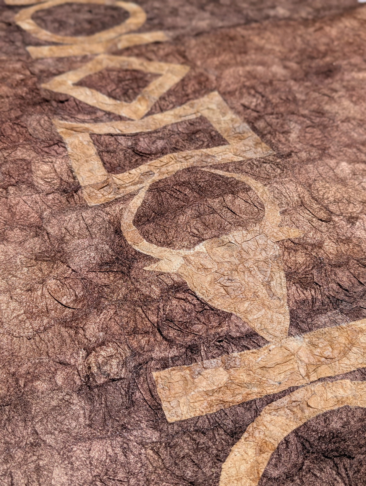 A close-up of a textured brown wild silk tapestry featuring a large, stylized beige geometric and organic pattern running diagonally across the surface.