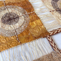 Closeup of wild silk textile wall hanging with circular geometric pattern and raffia tassels on edge. Nature-inspired, naturally dyed, fair trade, handmade. Made in Madagascar.