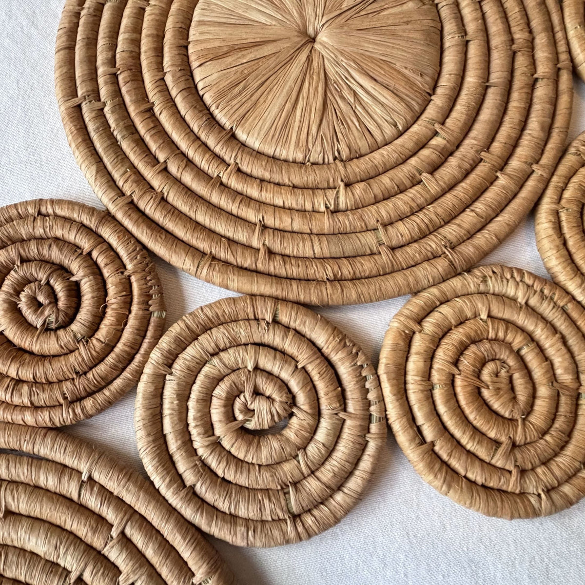 Closeup of raffia wall art / table runner with circular coiled wave pattern.  Handmade, fair trade certified, wildlife friendly, naturally dyed, sustainably sourced raw materials.  Made in Madagascar.